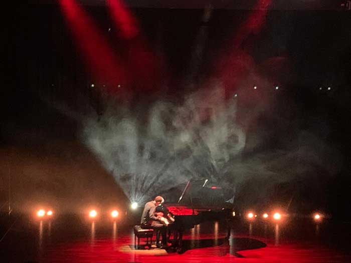 Farbige Lichtstimmung mit Personen auf einer Bühne die Klavier spielt